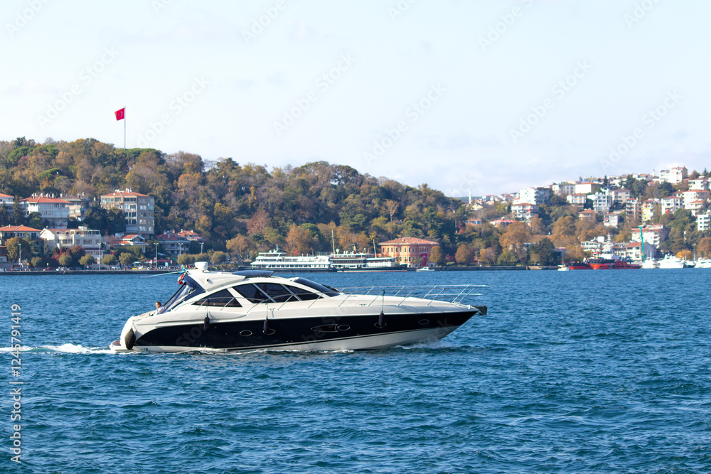 Obraz premium Luxury yacht sailing on the Bosphorus. Motor yacht on the blue sea. Watercraft idea concept. Horizontal photo. Landscape.