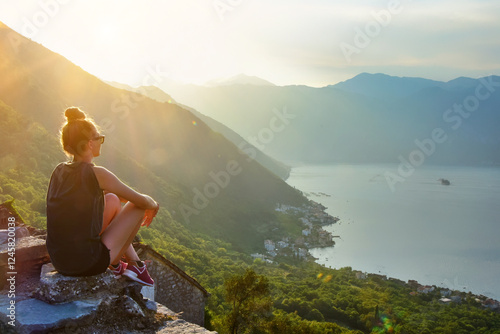 Photos Young woman sitting peacefully on top of a rock overlooking a bay landscape