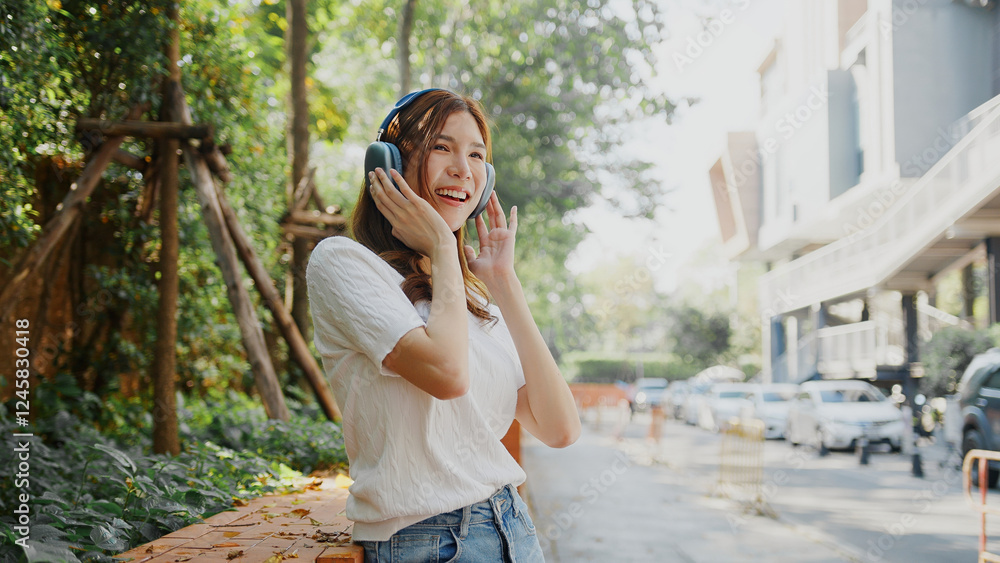 Attractive Enjoying music outdoors, woman with headphones smiles in sunny park. Her casual outfit and joyful expression create vibrant atmosphere. Asian Woman Lifestyle Attractive Enjoying music outdoors, woman with headphones smiles in sunny park. Her casual outfit and joyful expression create vibrant atmosphere. Asian Woman Lifestyle