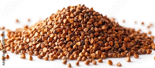 Buckwheat grains piled up on a white background showcasing their rich texture and color for culinary or agricultural use. photo