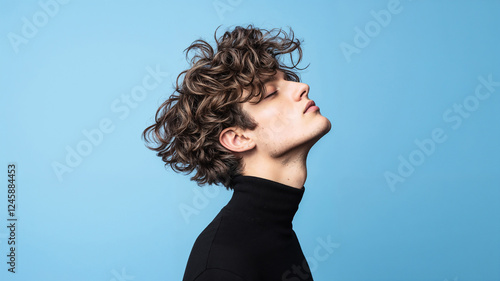 Young man with permanent wave hairstyle in black turtleneck against Sky Blue background