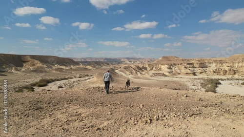 Man walking in the desert with his dog