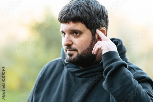 Deaf man wearing hearing aid demonstrates communication in natural setting