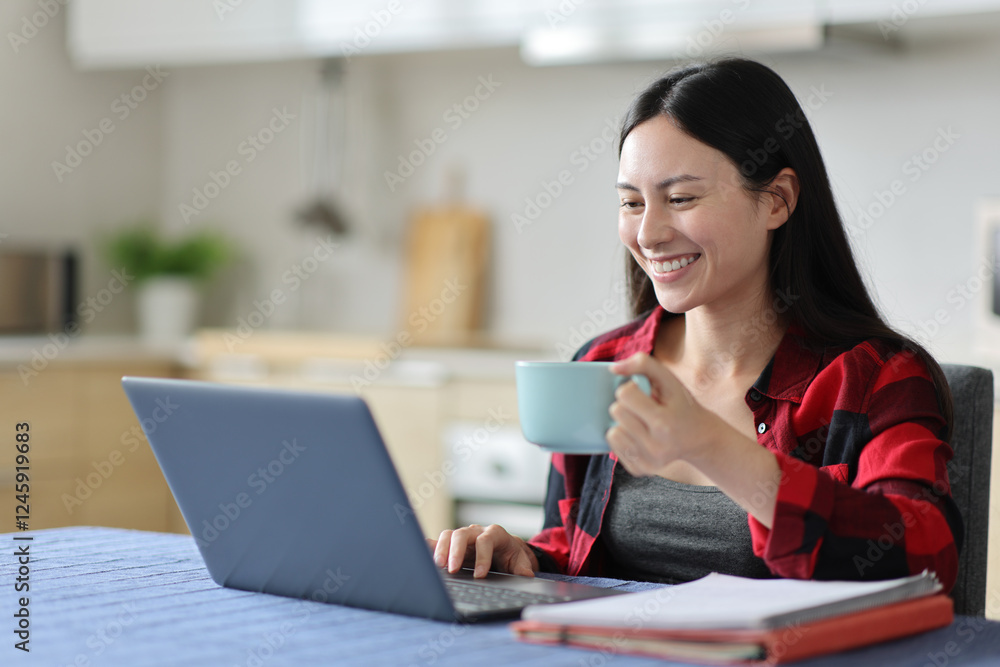Happy asian woman drinking and e-learning using laptop Happy asian woman drinking and e-learning using laptop