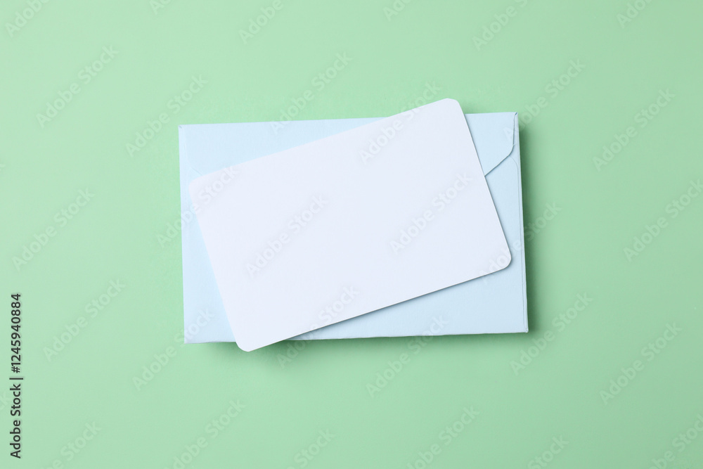 Blue envelope with white paper card on green background Blue envelope with white paper card on green background