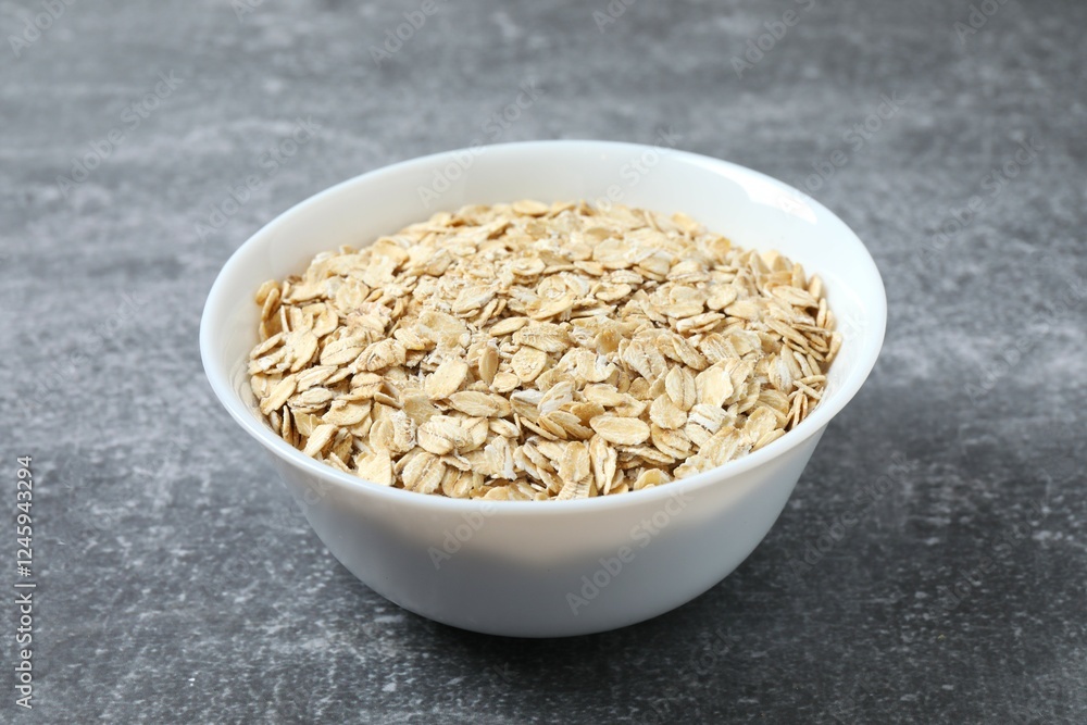 Composition with oatmeal flakes on gray background. Cooking breakfast Composition with oatmeal flakes on gray background. Cooking breakfast