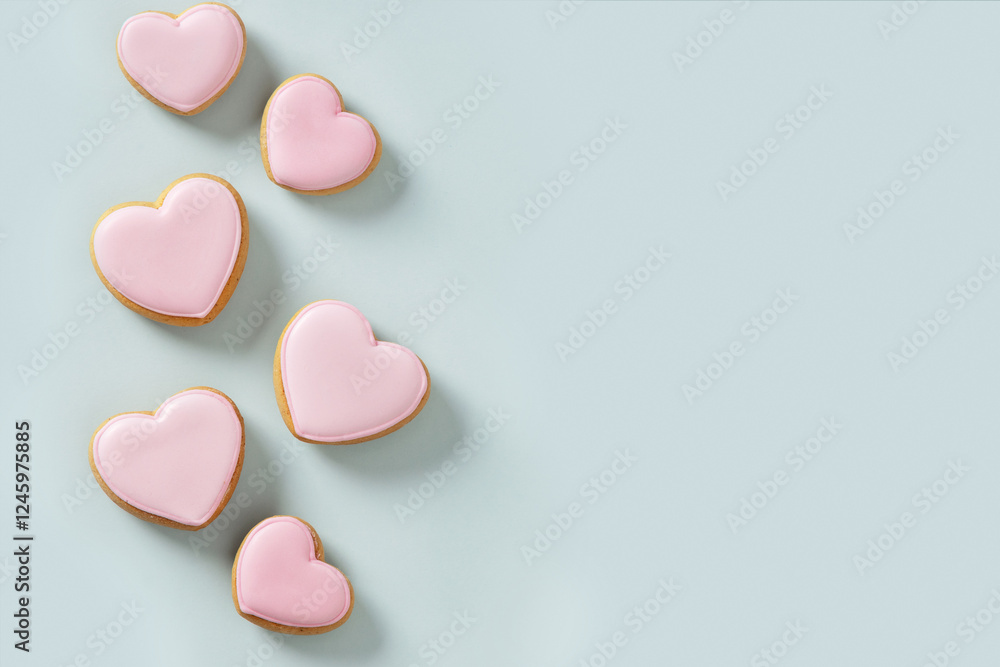 Seamless pattern of heart shaped cookies with pink glaze on blue background. Valentines day wallpaper or greeting card.