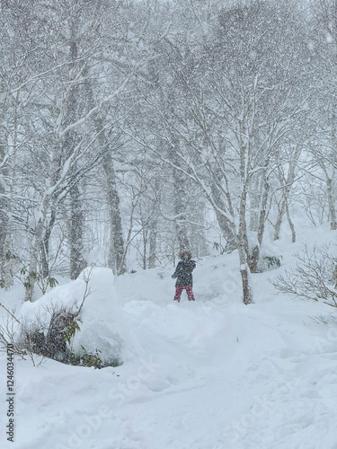 Unrecognizable young woman snowboarding offpiste during a snowstorm stops to rest and observe the snowy forest. Experienced female snowboarder stops to observe the wilderness engulfed in blizzard. photo