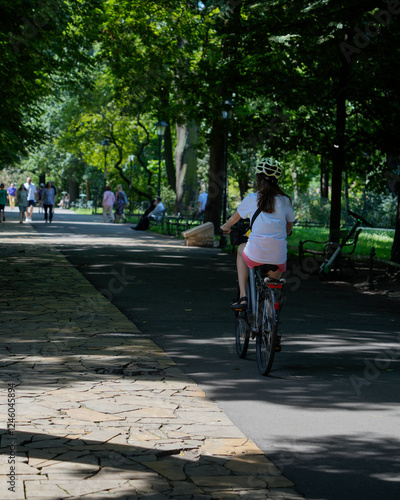 Wallpaper Mural A girl rides her bicycle along a scenic park path on a warm summer day. This vibrant scene embodies outdoor adventure and healthy living, capturing the joy of childhood and exploration in nature. Torontodigital.ca