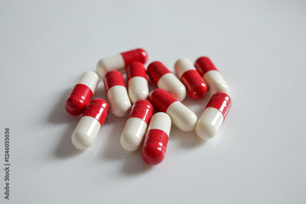 red and white capsules on a white surface with a hand reaching for ones medical pharmaceutical drugs self-medication medication adherence responsible drug use overdose awareness mental health red and white capsules on a white surface with a hand reaching for ones medical pharmaceutical drugs self-medication medication adherence responsible drug use overdose awareness mental health