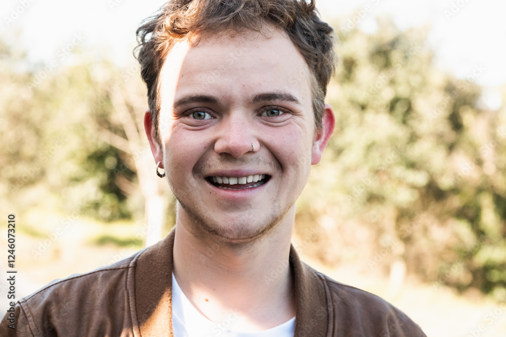 Smiling transgender man in a casual setting surrounded by greenery during daytime Smiling transgender man in a casual setting surrounded by greenery during daytime