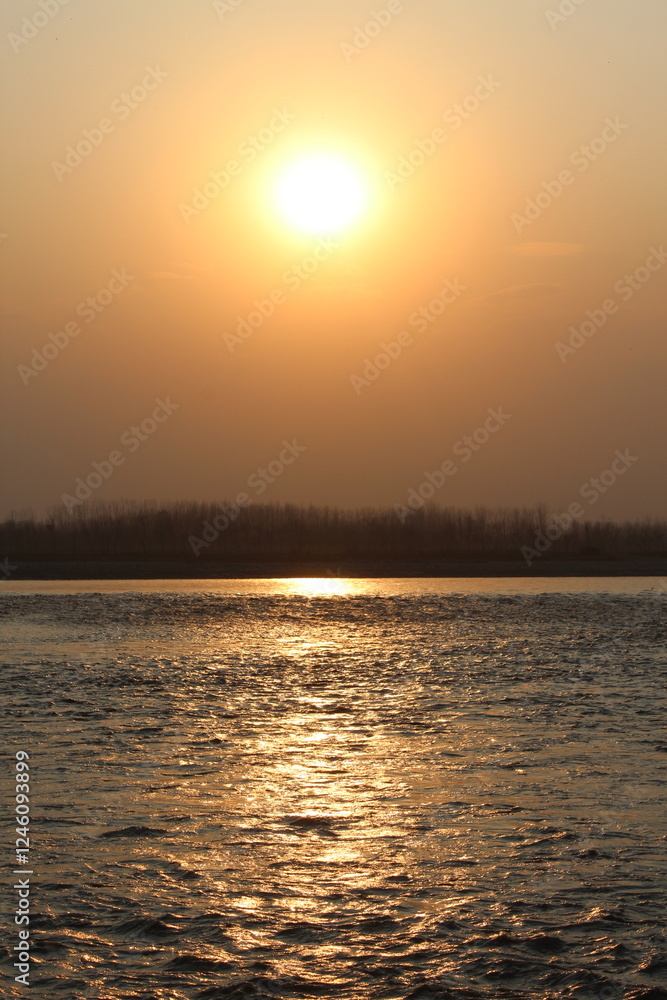 Naklejka premium Sunset over the ocean or river with a colourful sky and waves