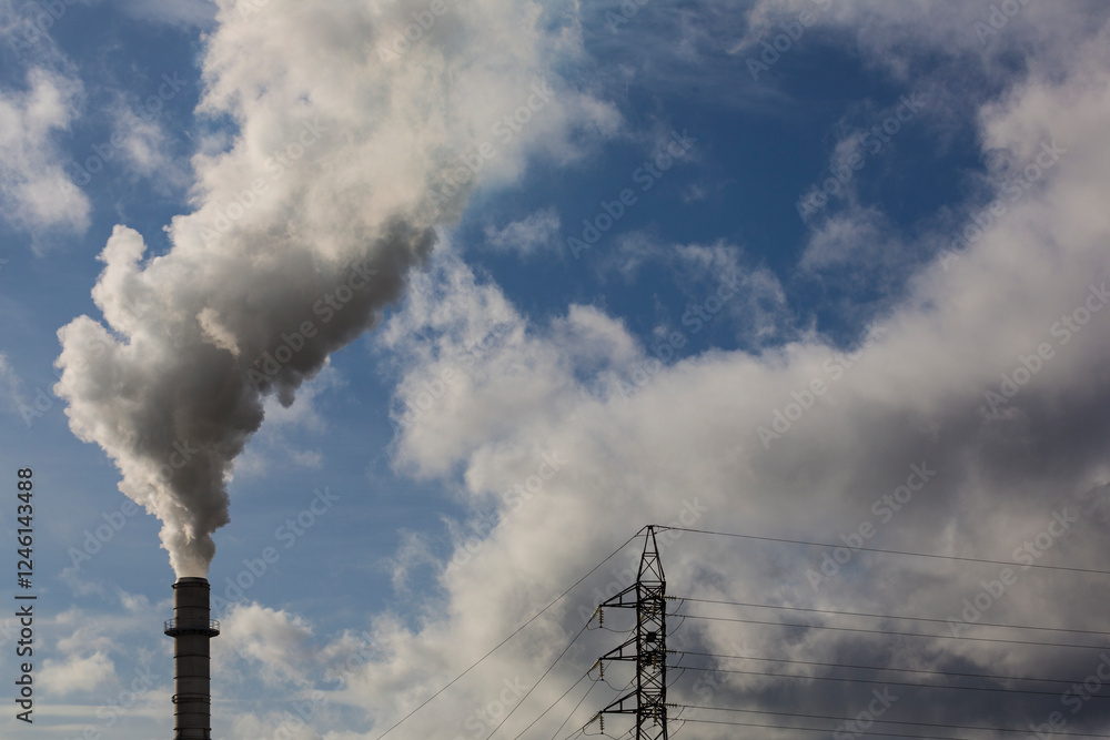 Chimney with smoke from a wood processing industry and an electric power pole. Electricity with blue sky and white clouds. Pollution Chimney with smoke from a wood processing industry and an electric power pole. Electricity with blue sky and white clouds. Pollution
