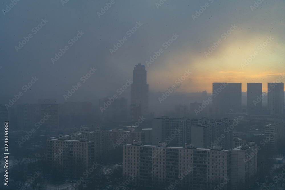 Fototapeta premium A snowstorm covers the big city, a gloomy sky with glimpses of the sun. Aerial shooting. Space for text.