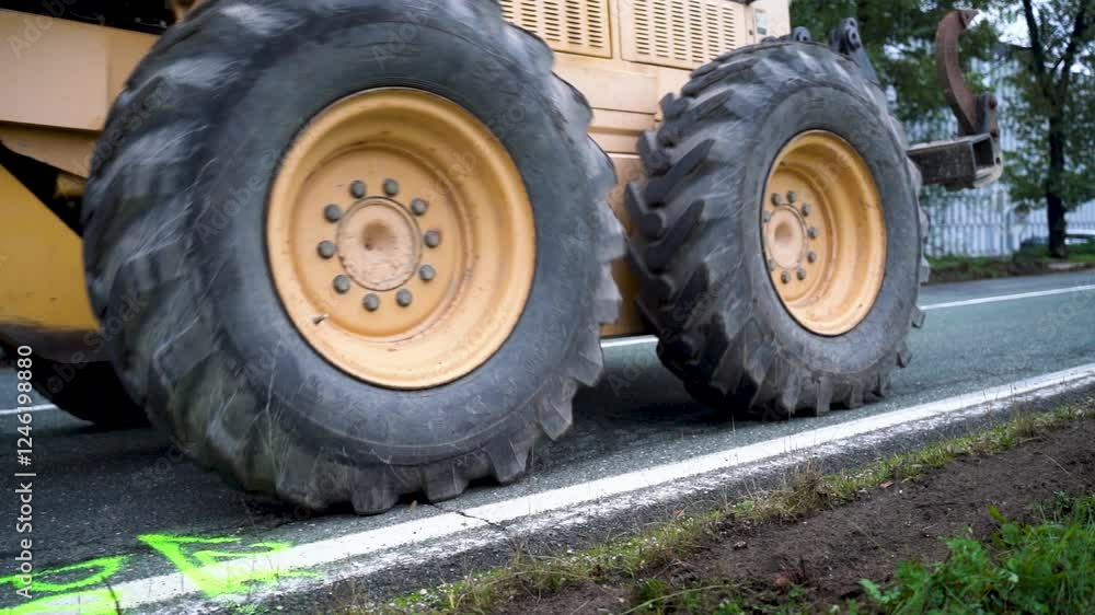 Close-up of Road Grader Clearing Grass from Road Edge at Construction Site for Asphalt Removal in Preparation of New Asphalt Layer Close-up of Road Grader Clearing Grass from Road Edge at Construction Site for Asphalt Removal in Preparation of New Asphalt Layer