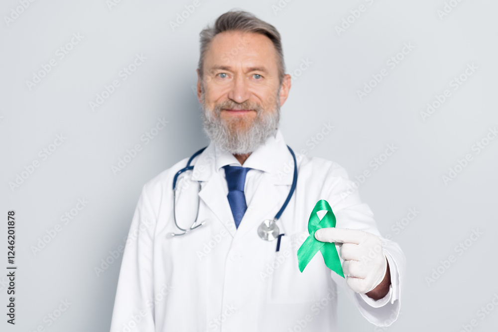 Senior male doctor holding a green awareness ribbon promoting health and healthcare causes Senior male doctor holding a green awareness ribbon promoting health and healthcare causes