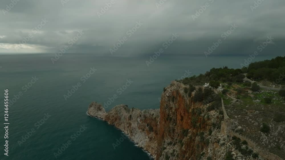 Drone view of epic clouds with rain over the sea and the Alanya fortress on the cliffs Drone view of epic clouds with rain over the sea and the Alanya fortress on the cliffs