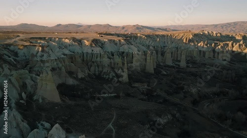 Drone flight between elongated unusual rock formations resembling chimneys or phalluses, illuminated by the sunset at the Love Valley in Cappadocia photo