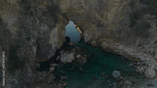 Cinematic side movement with a drone showing a hole in cliff where turquoise seawater flows into a natural pool at the secret beach of Kings Bay, Gazipasa, Turkey photo