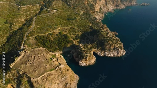 Aerial view of the ruins of Gazipaşa Fortress on a cliff above the blue Mediterranean Sea and small peninsulas of Kings Bay in Turkey, with banana plantations in the background photo