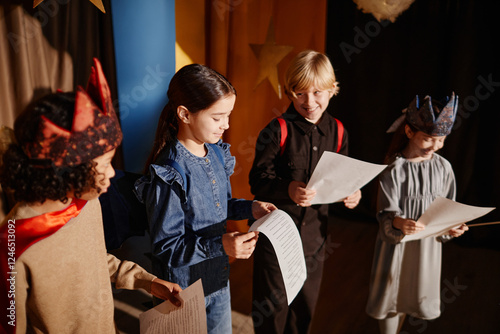 Fotografie Young students rehearsing for school play, some wearing costumes and holding scripts, happily engaging in theater activity