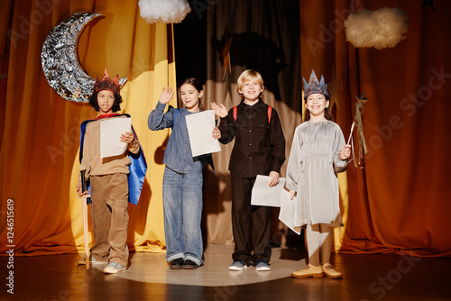 Foto Four children on stage during a school play, holding scripts and wearing costume