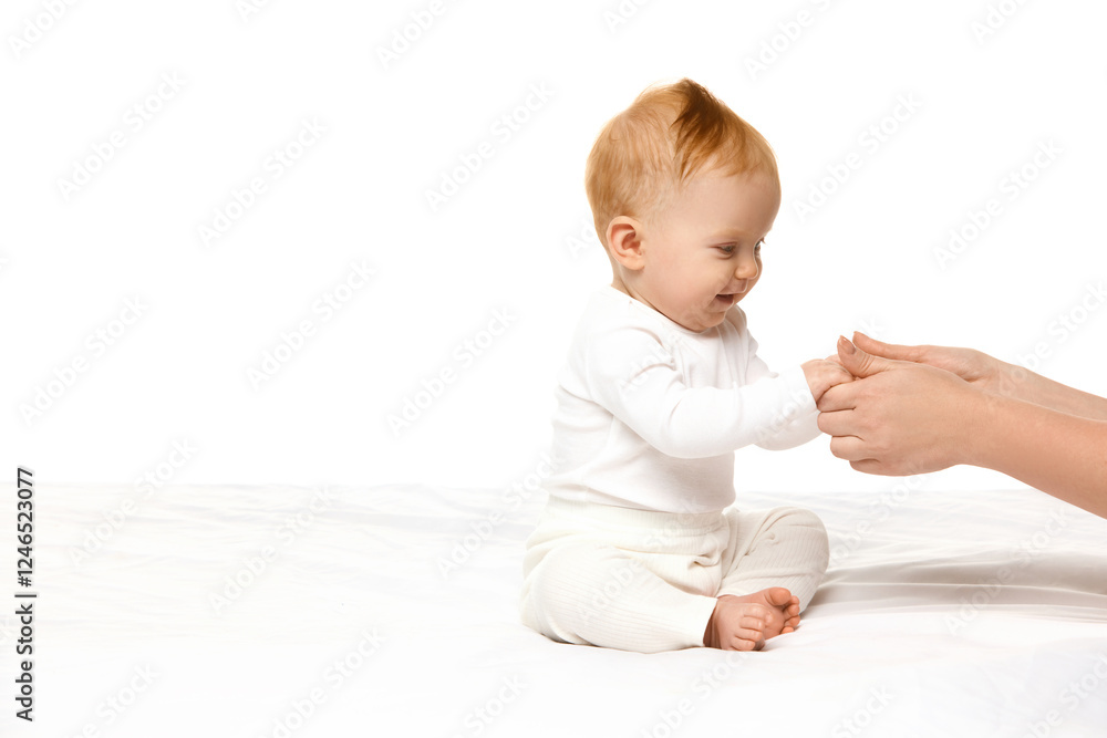 Happy, smiling baby girl, toddler sitting in bed, holding hands with mother against white studio background. Wellness. Concept of childhood, motherhood care. Copy space for ad Happy, smiling baby girl, toddler sitting in bed, holding hands with mother against white studio background. Wellness. Concept of childhood, motherhood care. Copy space for ad