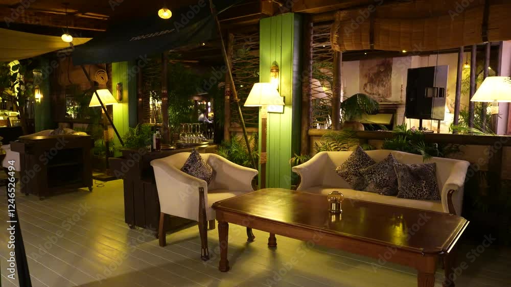 Elegant lounge area with armchairs, leopard-print pillows, wooden table, ambient lighting, and lush greenery in a cozy indoor setting. Elegant lounge area with armchairs, leopard-print pillows, wooden table, ambient lighting, and lush greenery in a cozy indoor setting.