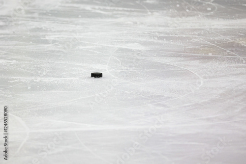 Small Black Ice Hockey puck laying on skated ice.