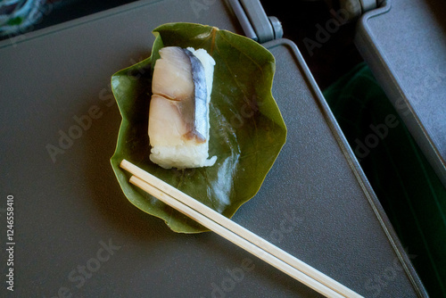 Sushi piece wrapped in a green leaf with chopsticks on a tray table in a Japanese train, near Kanazawa, Japan photo