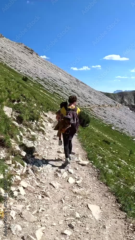 Tourists enjoying breathtaking mountain view while hiking in the italian alps during summer vacation Tourists enjoying breathtaking mountain view while hiking in the italian alps during summer vacation