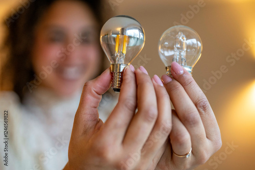 Woman holding LED and incandescent light bulbs in a softly lit room. Netherlands