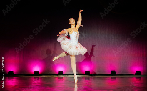 Ballerina gracefully performing on stage in a pink tutu with vibrant lighting. The Nutcracker, Bainbridge Island, USA