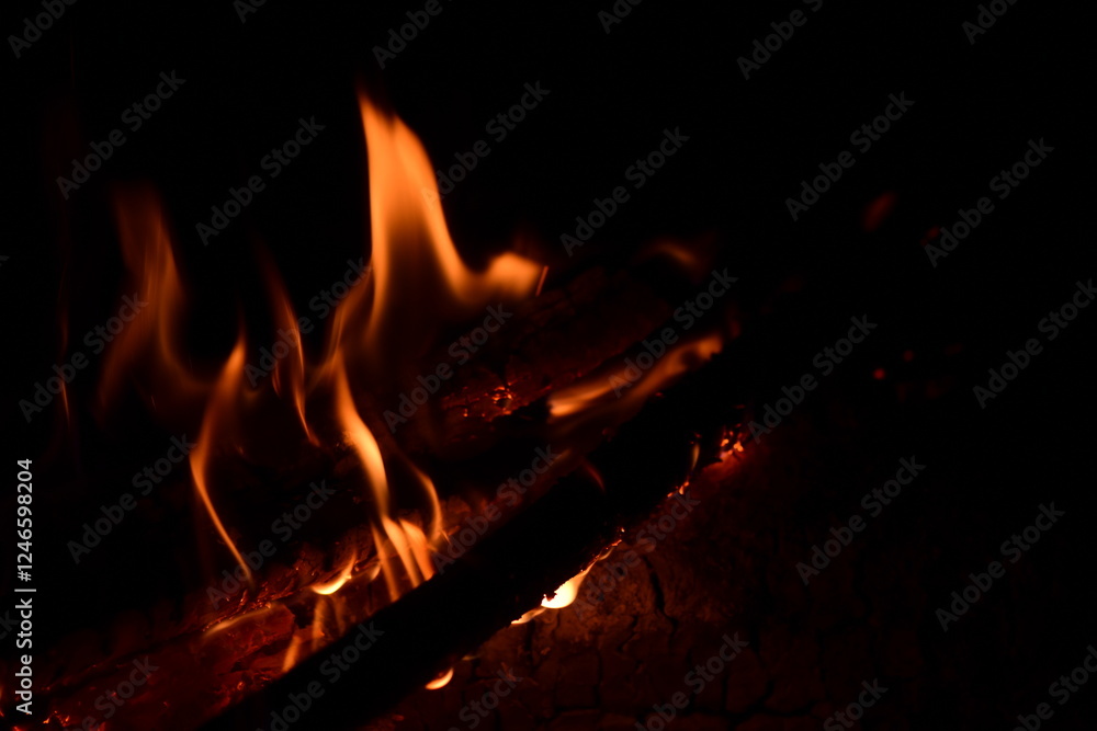 Fire flames on a black background. Burning firewood in the fireplace, close-up Fire flames on a black background. Burning firewood in the fireplace, close-up