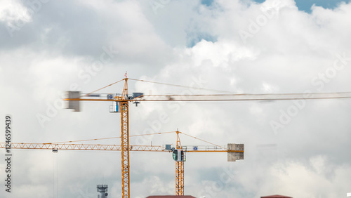 Big construction site including several cranes working and moving on a building complex, with cloudy sky timelapse photo