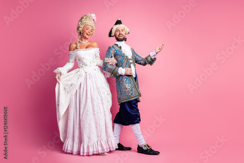 Elegant nobles in historic costumes posing against pink background at a themed event photo