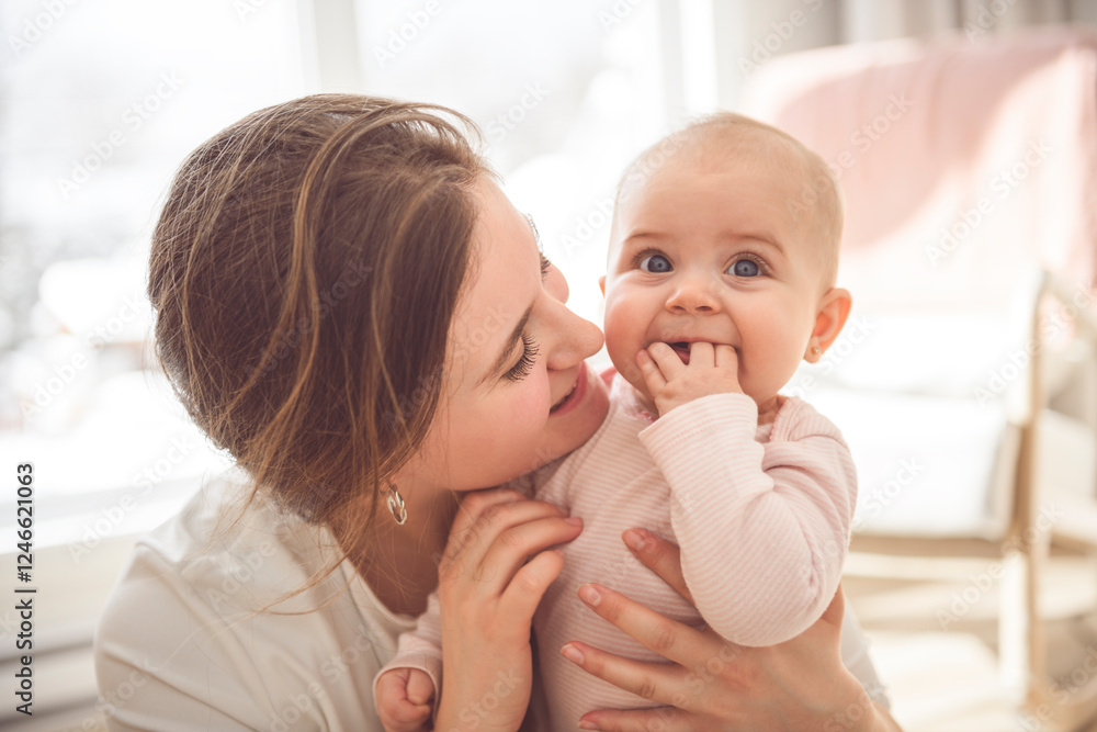 Cute small baby girl in bed at home. Woman holding little infant child.