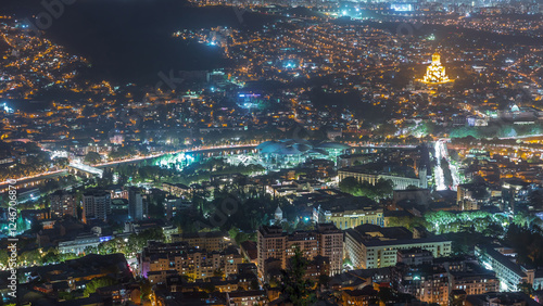 Illuminated Tsminda Sameba Cathedral or Holy Trinity Cathedral of Tbilisi and Public Service Hall aerial night timelapse Georgia photo