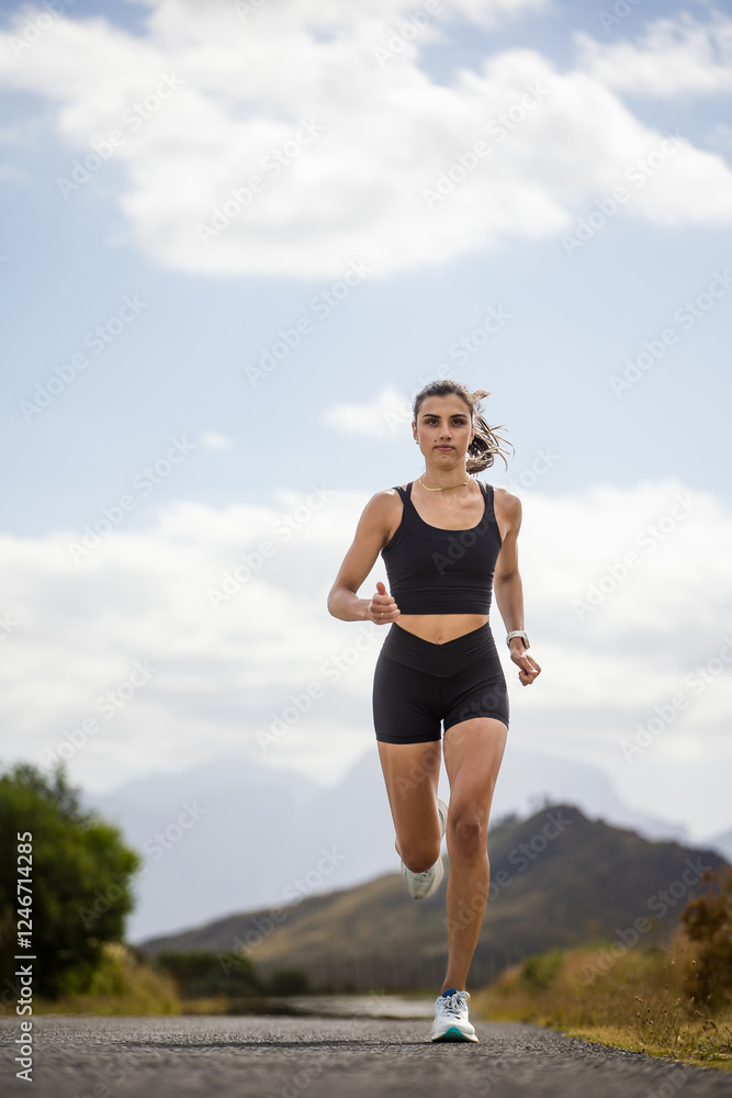Female athlete in black sportswear running on a rural road with a scenic mountainous backdrop, emphasizing endurance and outdoor fitness. Female athlete in black sportswear running on a rural road with a scenic mountainous backdrop, emphasizing endurance and outdoor fitness.