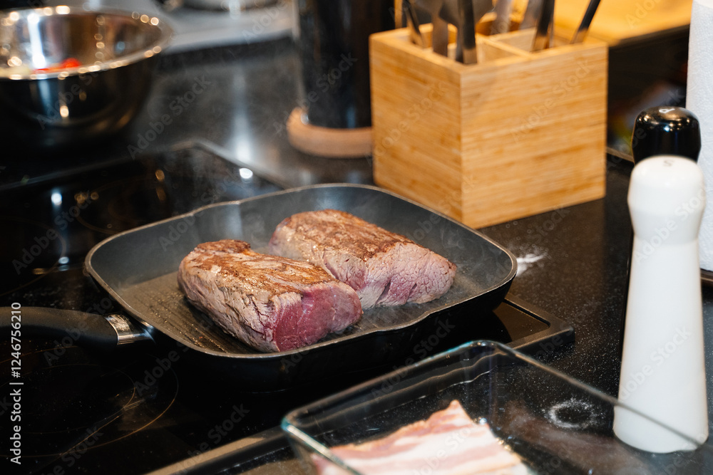 large pieces of beef steak are fried in a frying pan