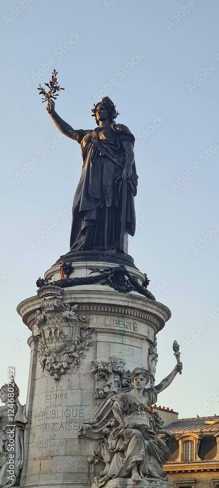Obraz premium Monument of Marianne at Place de la République in Paris, symbolizing liberty and the French Republic, captured against a clear sky.