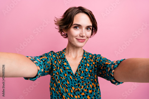 Photo of gorgeous pleasant girl with bob hairstyle dressed stylish shirt making selfie on frontal camera isolated on pink color background