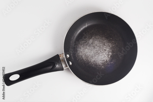 A frying pan with scratched nonstick surface, on white background.