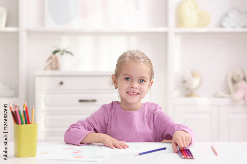 Happy girl at white table with drawing and pencils in kindergarten Happy girl at white table with drawing and pencils in kindergarten