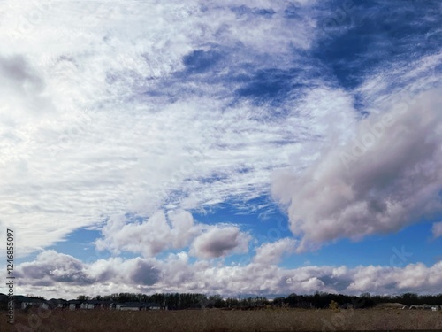 A beautiful dramatic sky with a different kinds of clouds are over a village
