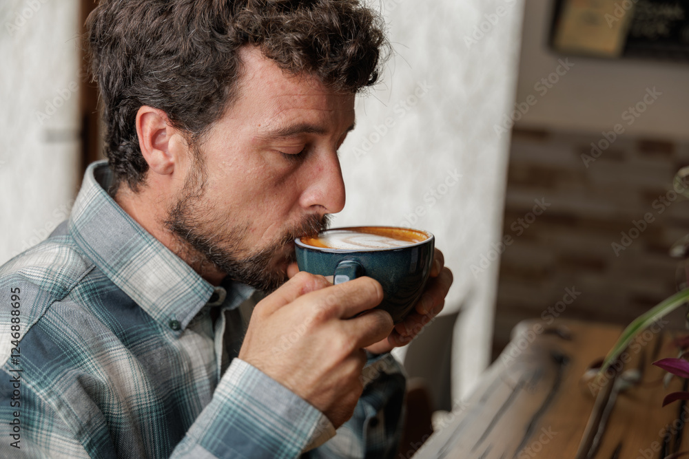 A young man enjoys a cup of specialty coffee with latte art to unwind from the work day. Copy space, close up. A young man enjoys a cup of specialty coffee with latte art to unwind from the work day. Copy space, close up.