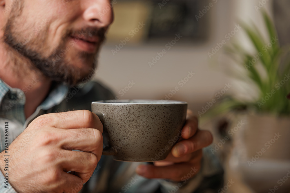 A young man enjoys a cup of specialty coffee with latte art to unwind from the work day. Copy space, close up. A young man enjoys a cup of specialty coffee with latte art to unwind from the work day. Copy space, close up.