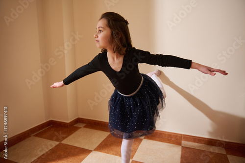 Young girl practicing ballet in a brightly lit room in elegant dancewear photo