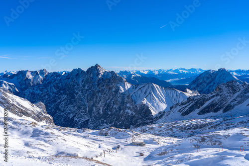 Stunning aerial panorama view of snow covered peaks of Austrian Alps in Tyrol from Zugspitzplatt on a sunny day with blue sky and cloud in winter, Garmisch-Partenkirchen, Bavaria, Germany