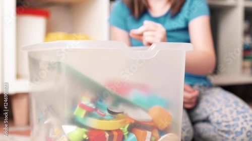 Beautiful child girl cleans up her toys. Little girl tydies up her room.